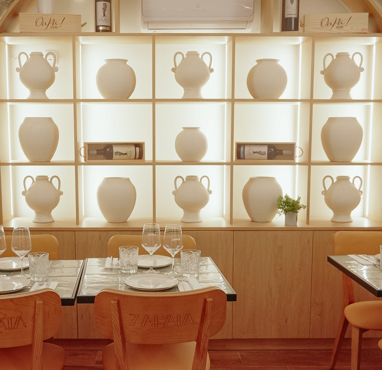 Room with a lit shelf of clay jugs and set tables