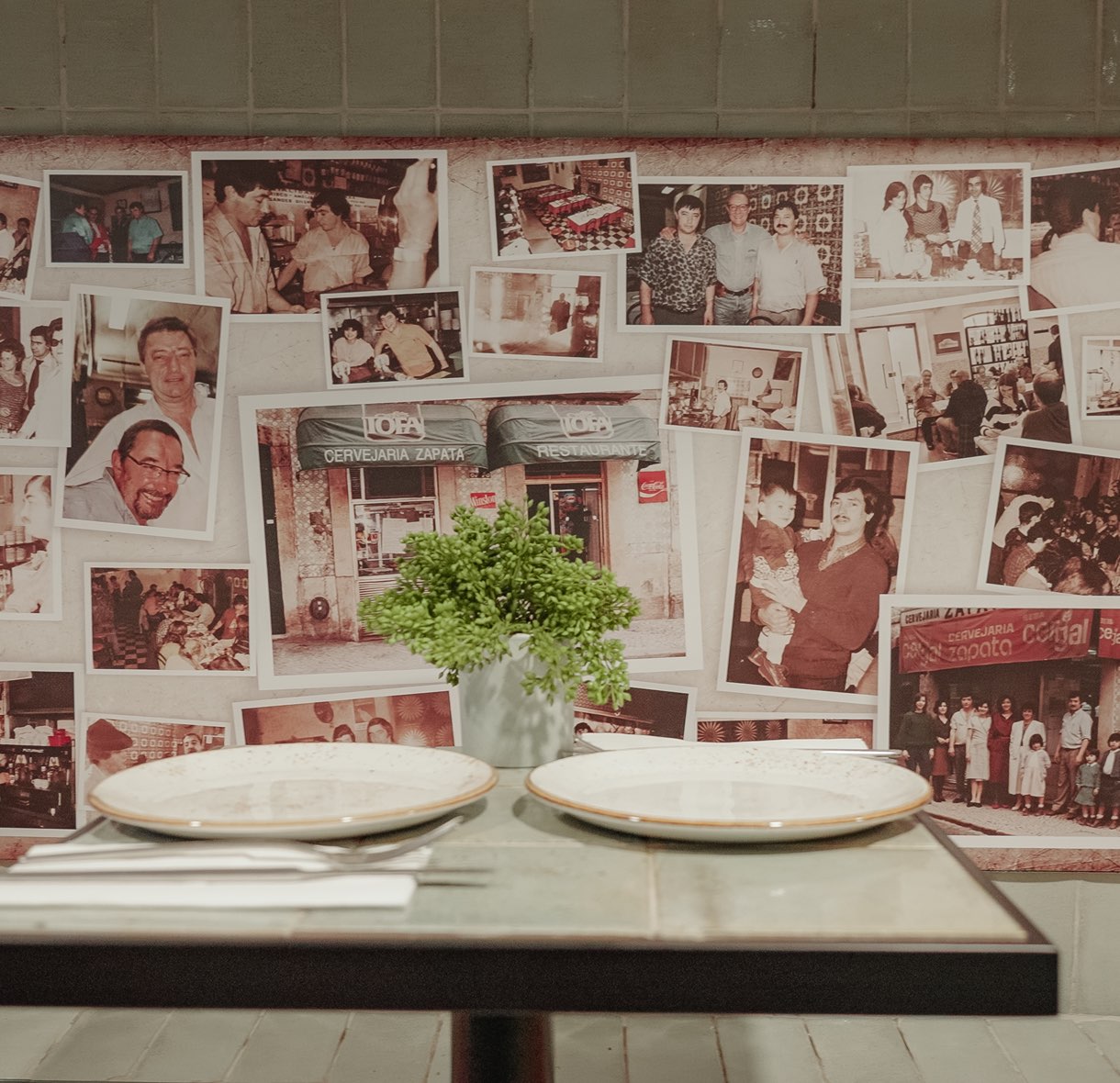 Table set by the wall of old photographs of the Cervejaria Zapata families
