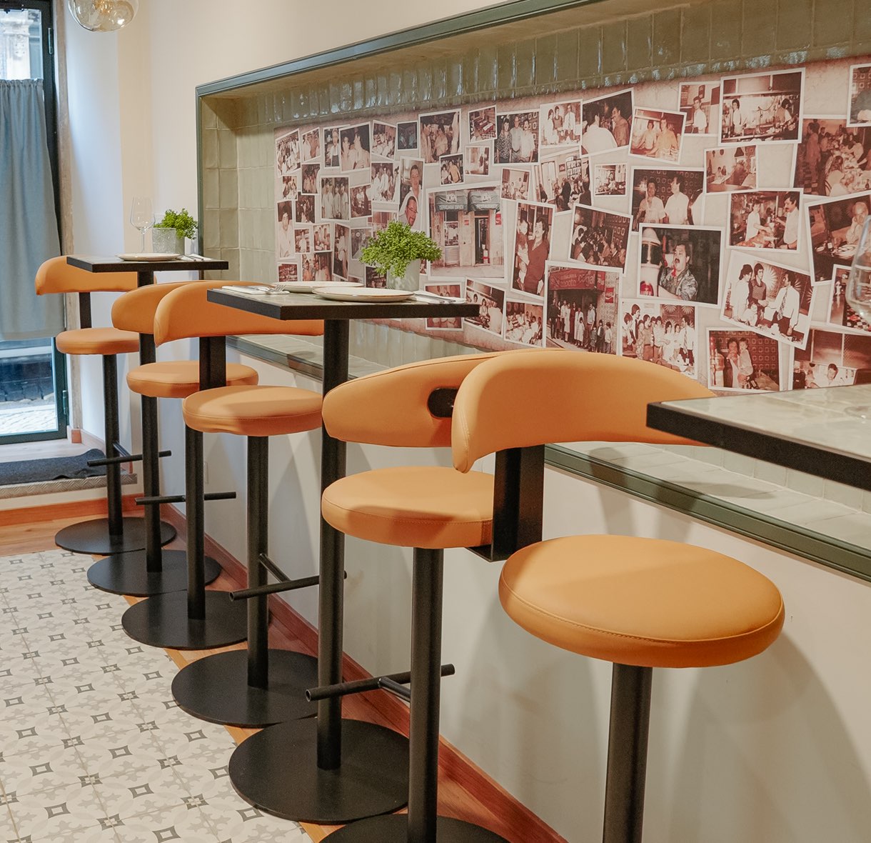 High tables and stools by the wall of family photographs